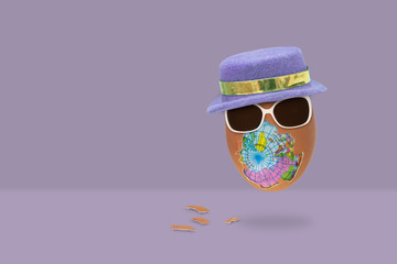 Fototapeta premium The shelled egg has an globe inside with glasses and hat is flying on purple background.
