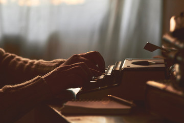 Young man writing on old typewriter.