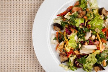 Eggplant salad with vegetables and walnuts on a white plate.