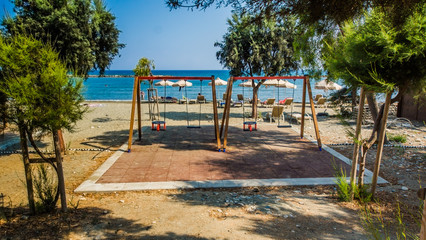 wooden swing on the Beautiful beach. Sunbeds with umbrella on the sandy beach near the sea. Summer holiday and vacation concept. Inspirational tropical beach