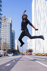 Side view young black man wearing casual clothes jumping in urban background. Lifestyle concept. Millennial african guy wearing sunglasses outdoor