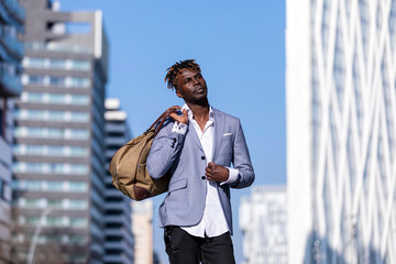 Front view black young man urban casual fashion in the street. Wearing black elegant jacket, jeans,...