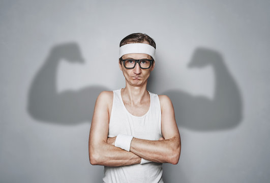 Funny sport nerd with shadow muscle arms over gray wall with copy space