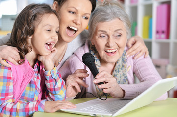 Portrait of happy family sitting at table and singing karaoke