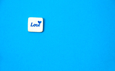 White square wood with love word written on blue sky background, love concept.