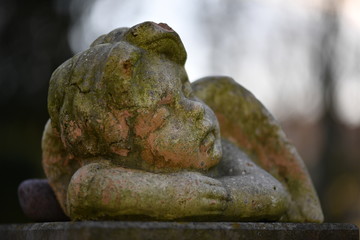 A moss covered sandstone sculpture of an angel.