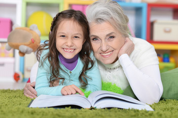 Fototapeta na wymiar Portrait of grandmother reading book with granddaughter