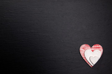 Rot weiße Herzen aus Holz auf dunkler Steinplatte
