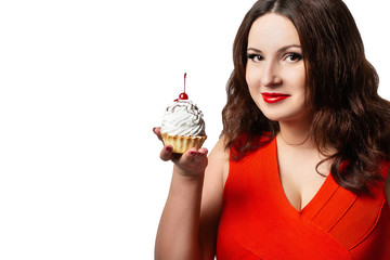 A woman in a red dress holding a cake with cream and a cherry. The girl looks at the sweetness and wants to eat it. Isolated portrait on white background