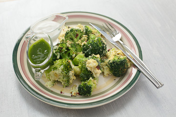 fried broccoli with egg on a plate on a gray background with sauces