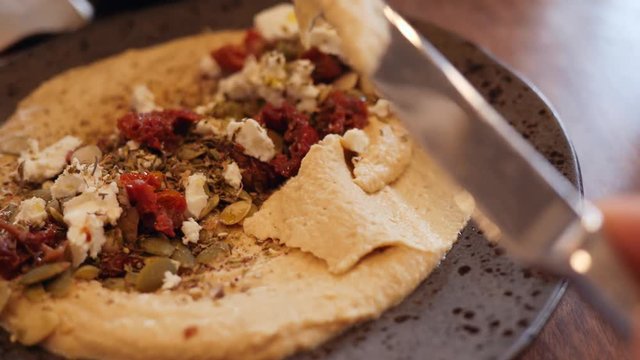 Spreading healthy vegan hummus on a piece of full grain bread