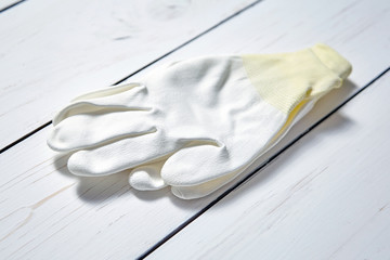 White knitted polyester yarn hand protection gloves on wooden table