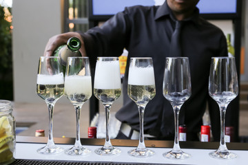 barman pouring champagne in six glasses with blue berries