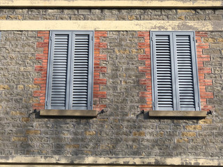 Fototapeta na wymiar Old window with blue shutters on a brick house