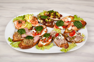 Meat sandwiches with vegetables in an assortment on a white dish.