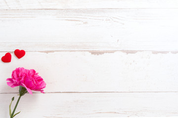 May mothers day concept photography - Beautiful carnations and hearts shape with white empty card isolated on a bright wooden table, copy space, flat lay, top view, mock up
