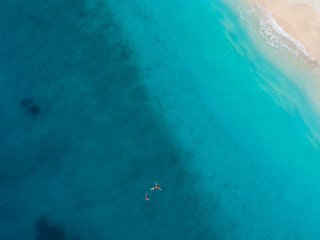 Man and a woman swimming in the clear and transparent turquoise water of Mediterranean sea. Aerial top down shot