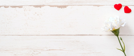 May mothers day concept photography - Beautiful carnations and hearts shape with white empty card isolated on a bright wooden table, copy space, flat lay, top view, mock up