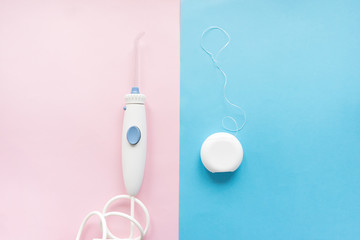 oral irrigator versus floss top view on pink and blue background
