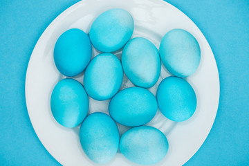 top view of blue easter eggs on plate isolated on blue