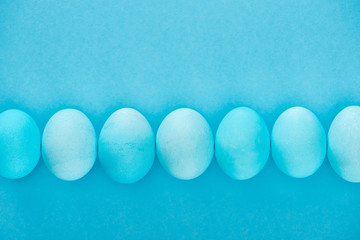 top view of blue easter eggs in row isolated on blue