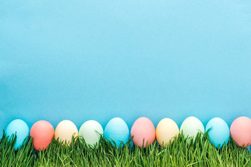 Top view of colorful easter eggs on grass isolated on blue