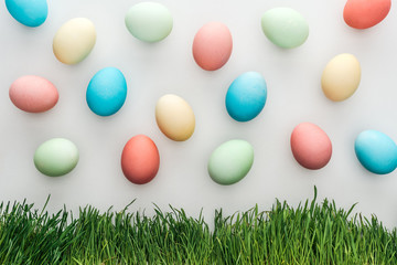 Top view of painted pastel easter eggs isolated on grey with grass
