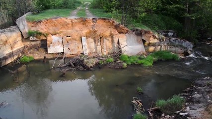 Destroyed bridge dam over the river in the forest