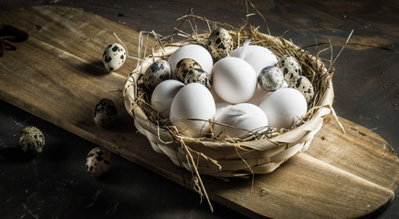 Chicken and quail eggs on wooden background