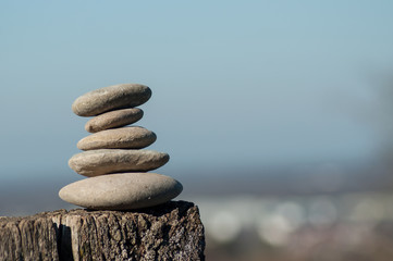 Closeup of stone balance on wooden fenceon blurred rural landscape background