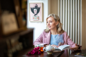 Walk around town.Blonde girl in pink and blue tones.City cafe, reading a book.