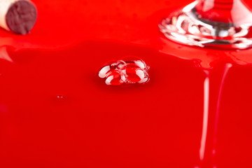 spill over red wine with bubbles near a glass cup and a wooden cork