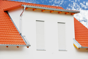 Einfamilienhaus-Neubau mit rotem Ziegeldach, Edelstahl-Abschlussblechen und Beton-Schleppgaube
