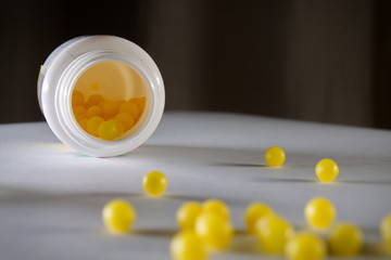 Soft focus shot of small yellow ball pills with attention to the inside of the bottle