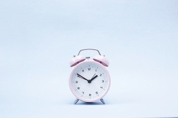 Pink ringing alarm clock on blue background