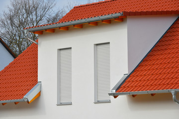 Einfamilienhaus-Neubau mit rotem Ziegeldach, Edelstahl-Abschlussblechen und Beton-Schleppgaube