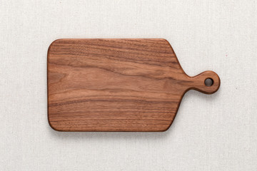 Walnut handmade wood cutting board on the linen. 