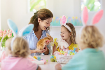 Mother and kids, family coloring Easter eggs.