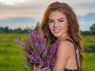 Smiling girl in a field with lavender flowers in her hands.