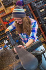 Pretty girl repairing ski in the workshop