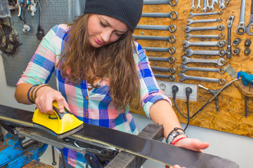 Pretty girl waxing ski in the workshop