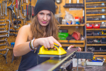 Pretty girl waxing ski in the workshop