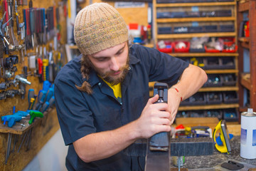 Bearded guy repairing ski in the workshop