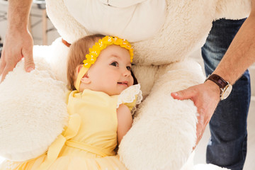 Little girl in a yellow dress hugs a big toy bear