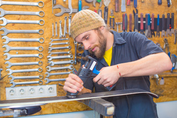 Bearded guy repairing ski in the workshop