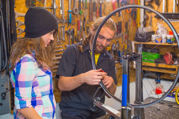 Young couple repairing bicycle in the workshop