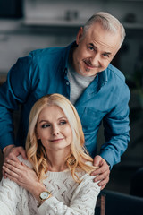 handsome man embracing cheerful wife at home