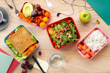 Fototapeta na wymiar Top view shot with healthy lunch dishes variety: salad with grains, salmon and rice, sandwich and fruit snacks. Daily office or school lunch concept