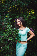 Wonderful spring. Cute young girl posing on nature near lilac blooming.