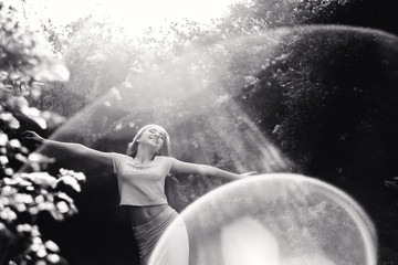 Obraz premium Wonderful spring. A beautiful young girl enjoys nature and sunlight among the blossoming lilac.